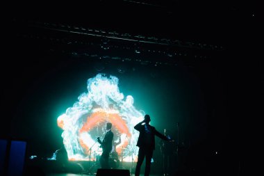 Parlak spot ışıklarının kırmızı mavi ışıklarıyla sahnede şarkı söyleyen şarkıcı ve rock grubunun bulanık renkli fotoğrafı