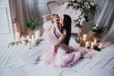 Anne ve sevimli kız stüdyoda pembe elbiseler içinde.