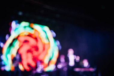 Parlak spot ışıklarının kırmızı mavi ışıklarıyla sahnede şarkı söyleyen şarkıcı ve rock grubunun bulanık renkli fotoğrafı