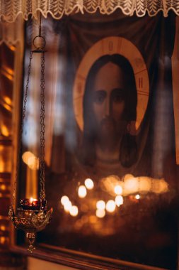 Kilisede ikonun yanında asılı yanan mum.
