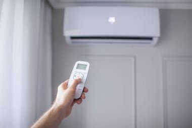 Odanın içinde güzel bir odada uzaktan kumandalı bir klima ve gri bir duvar var.