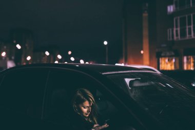 Güzel bir kadın akşam arabada oturuyor.