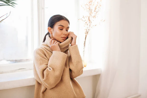 beautiful woman in sweater stay near window at day time