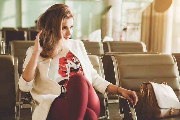 若い女性が椅子に座って飛行機を待っています — ストック写真
