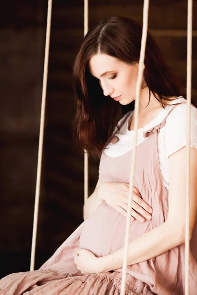 Έγκυος Γυναίκα Ροζ Φόρεμα Κάθεται Μια Κούνια Ξύλινο Φόντο — Φωτογραφία Αρχείου