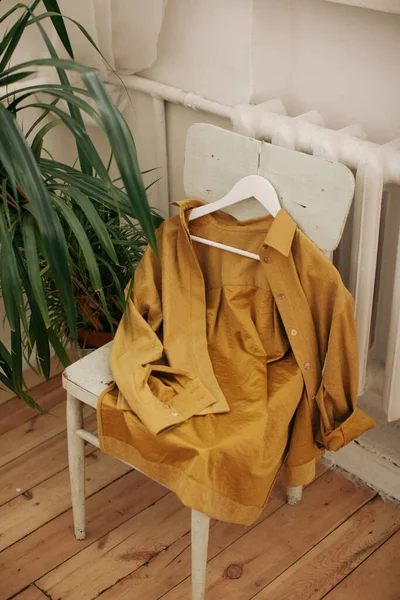 clothes on the old wooden chair with plants on background