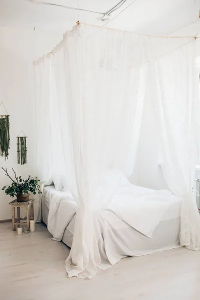 cozy light bedroom in a minimalist Scandinavian style bedroom, canopy bed, blanket pillows, plant. morning sunny photo