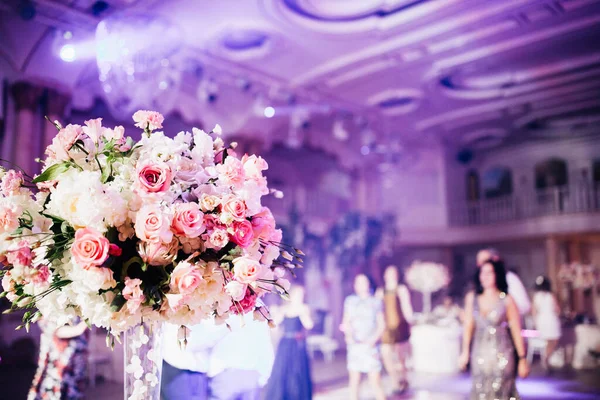 interior of luxury beautiful wedding room with flowers and people dancing on background