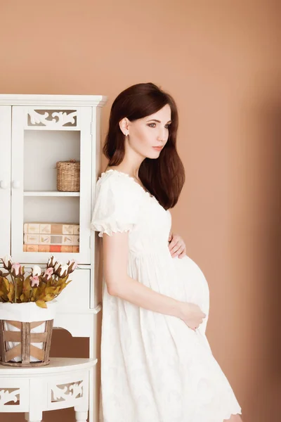 Όμορφη Έγκυος Μελαχρινή Γυναίκα Λευκό Φόρεμα Φόντο Μπεζ Τοίχο — Φωτογραφία Αρχείου