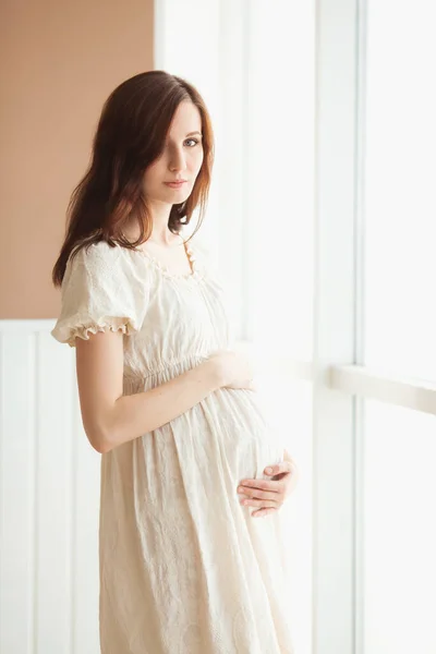 Vacker Gravid Kvinna Vit Klänning Står Nära Fönstret — Stockfoto