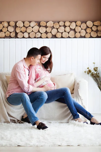 Güzel müstakbel ebeveynler, hamile bir kadın ve kocası koltukta oturuyor.