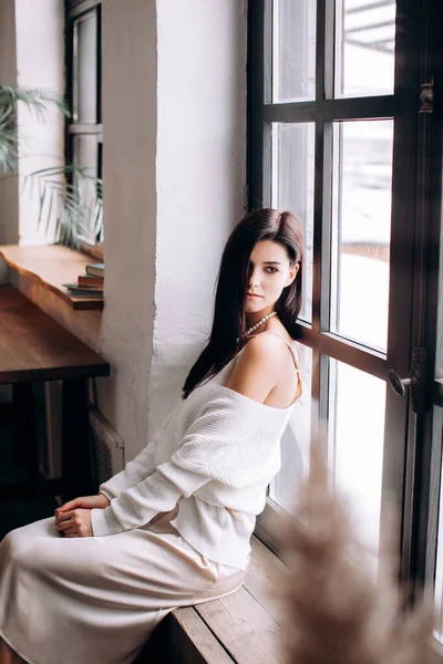 Güzel esmer kadın pencereye bakıyor.