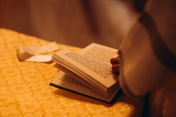 cropped image of priest touching bible in church