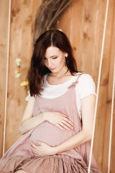 Schwangere Rosa Kleid Sitzt Auf Einer Schaukel Auf Einem Hölzernen — Stockfoto