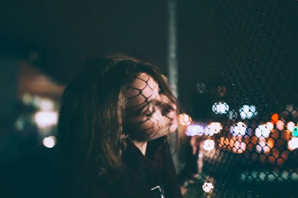 美しい若いブロンドの女性は夜にワイヤーフェンスの近くに滞在 — ストック写真