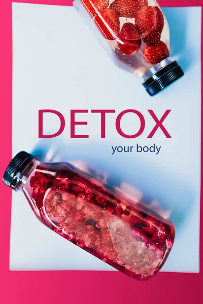 Detox tatlı suyu köpüklü bardaklarda çilek ve ahududu ve yumuşak pastel mavi arka planda şişe ile doldurdu, kopyalama alanı. Soğuk yaz içkisi. Maden suyu. Üst görünüm.