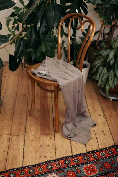 clothes on the old wooden chair with plants on background