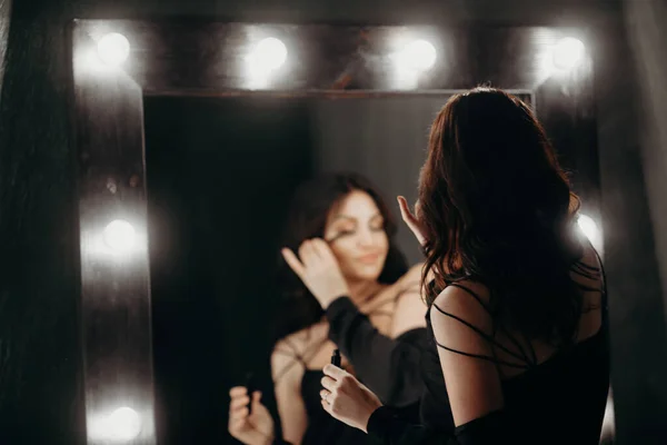 Bella Donna Compone Vicino Grande Specchio Con Lampadine Sfondo Scuro — Foto Stock