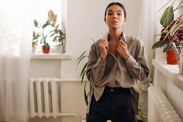 şık genç bayan bitkilerle dolu büyük pencerenin yanında kal.