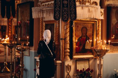 Kilisedeki simgelerin yanında duran kadının arka planı