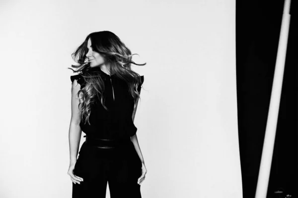 Siyah giyinmiş güzel sarışın kadının moda fotoğrafı beyaz arka planda duruyor.