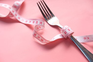 Pembe arkaplanda ölçü bandı olan çatal 