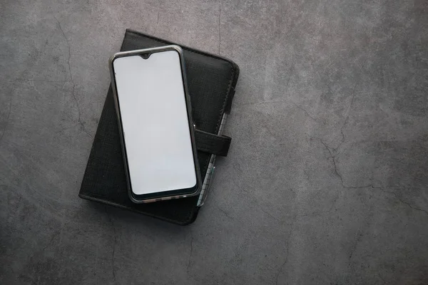Telepon pintar dengan layar kosong dan buku harian dengan latar belakang abu-abu — Stok Foto