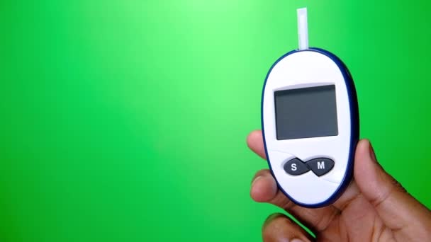 Человек рука держит диабетические инструменты измерения на зеленом фоне — стоковое видео
