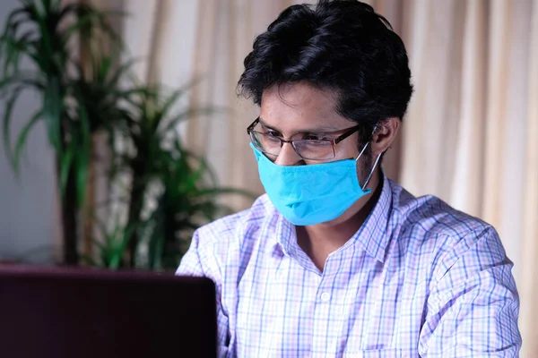 Gefrustreerde man in het gezicht masker werken op laptop op kantoor — Stockfoto