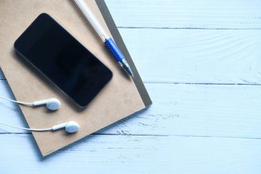  Boş ekranlı akıllı telefon ve tahta arka planda bir not defteri 