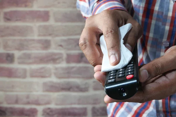 close up of person hand cleaning tv remote