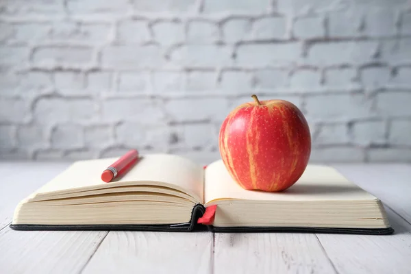Gros plan de pomme et crayon sur livre ouvert sur table — Photo
