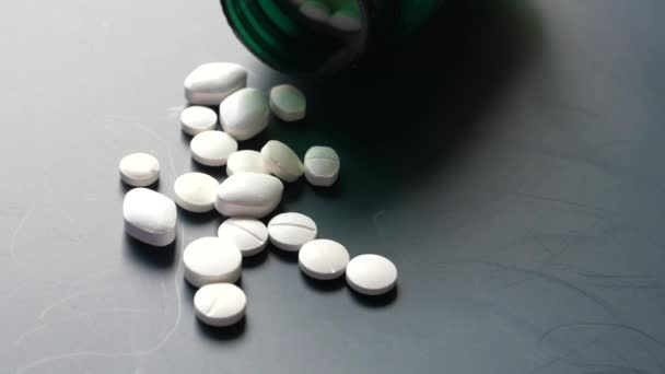 Primer plano de píldoras blancas derramándose sobre fondo oscuro — Vídeos de Stock