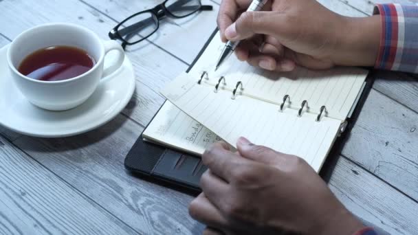 Pessoa mão escrevendo no bloco de notas na mesa de escritório — Vídeo de Stock