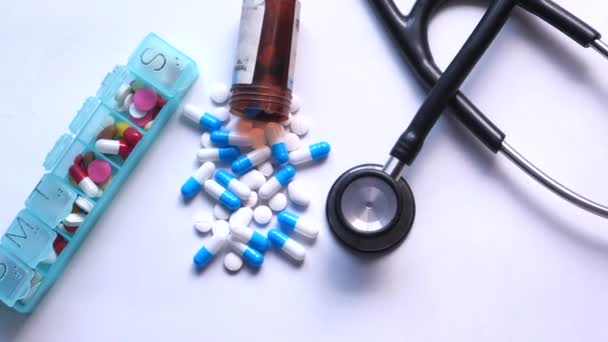 Nahaufnahme von farbenfroher Kapsel, Tablettenbox und Stethoskop auf weißem Hintergrund — Stockvideo