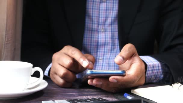 Hombre joven en traje usando teléfono inteligente en el escritorio de la oficina — Vídeo de stock