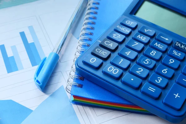 Primer plano de la calculadora azul y gráfico financiero en la tabla. — Foto de Stock