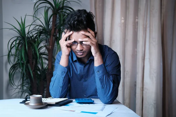 Üzgün ve stresli bir genç, nedensel bir elbise giymiş, evden çalışıyor.