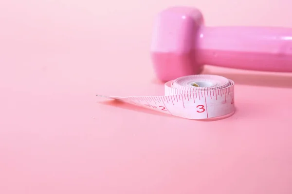Close-up de haltere e fita métrica em rosa — Fotografia de Stock