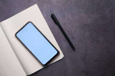 Gri arkaplanda akıllı telefon ve kalemin üst görünümü 