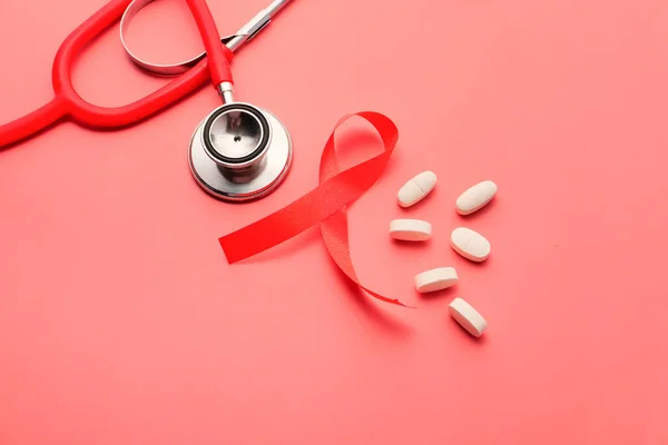 Red ribbon HIV, pills and stethoscope on pink background. — Stock Photo, Image