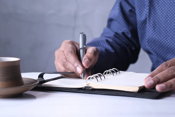 Молодой человек пишет на блокноте за рабочим столом — стоковое фото