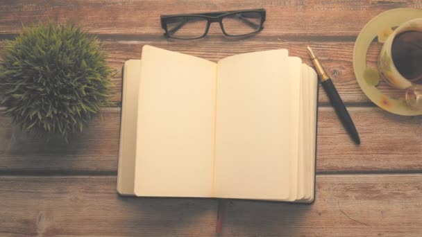 Sudut tinggi tampilan buku harian terbuka, teh dan kacamata di atas meja kayu — Stok Video