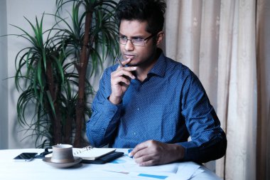 İç işlerinde çalışan düşünceli Asyalı genç adam. 