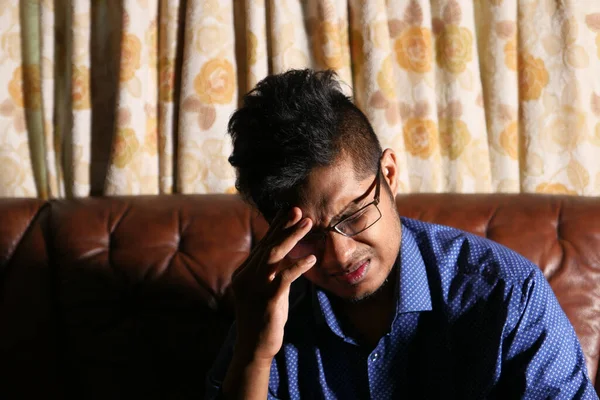 Jongeman gefrustreerd en lijden hoofdpijn zittend op de bank — Stockfoto