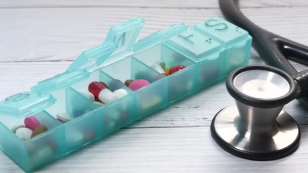 Zavřít krabici na pilulky a stetoskop na stole — Stock video