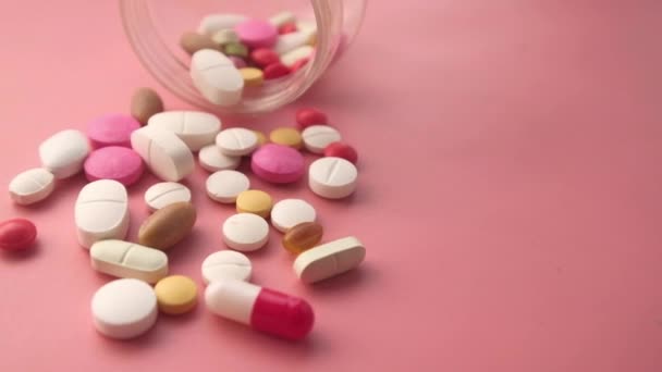 Close-up van kleurrijke pillen en medicijnen morsen van contianer — Stockvideo