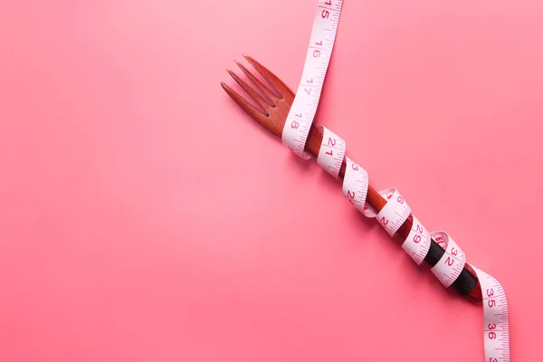 Garfo com fita métrica em fundo rosa — Fotografia de Stock