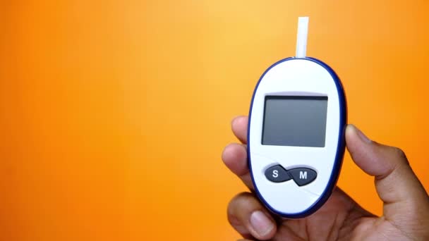 Mann hält diabetisches Bluttestset Glukometer auf farbigem Hintergrund . — Stockvideo