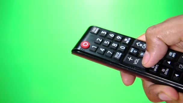 Närbild av man hand hålla tv fjärrkontroll mot grön skärm — Stockvideo